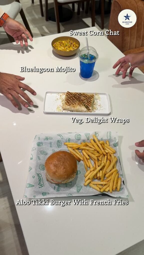 Sweet Corn Chat, Blue Lagoon Mojito, Veg Delight Wraps and Aloo Tikki Burger on a table at Bluestar Café